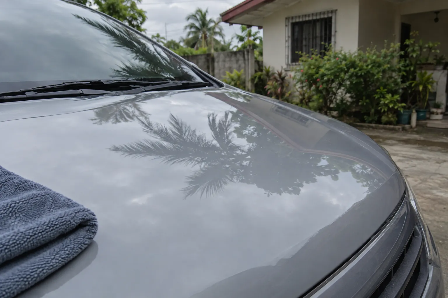 A washed and dried bonnet reflecting palms and a rooftop, a folded drying towel at its edge.