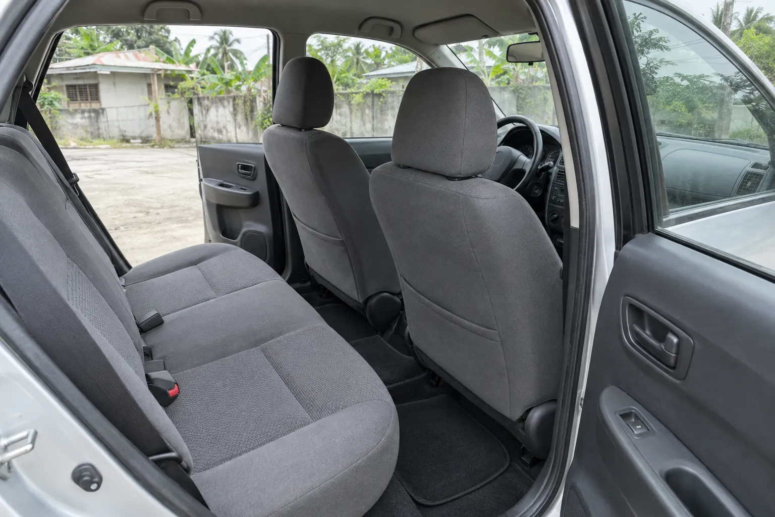 The cleaned rear seats and mats of an ordinary car, seen through its open back door.